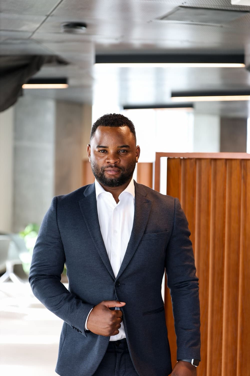 A confident man in a navy business suit standing in a modern office