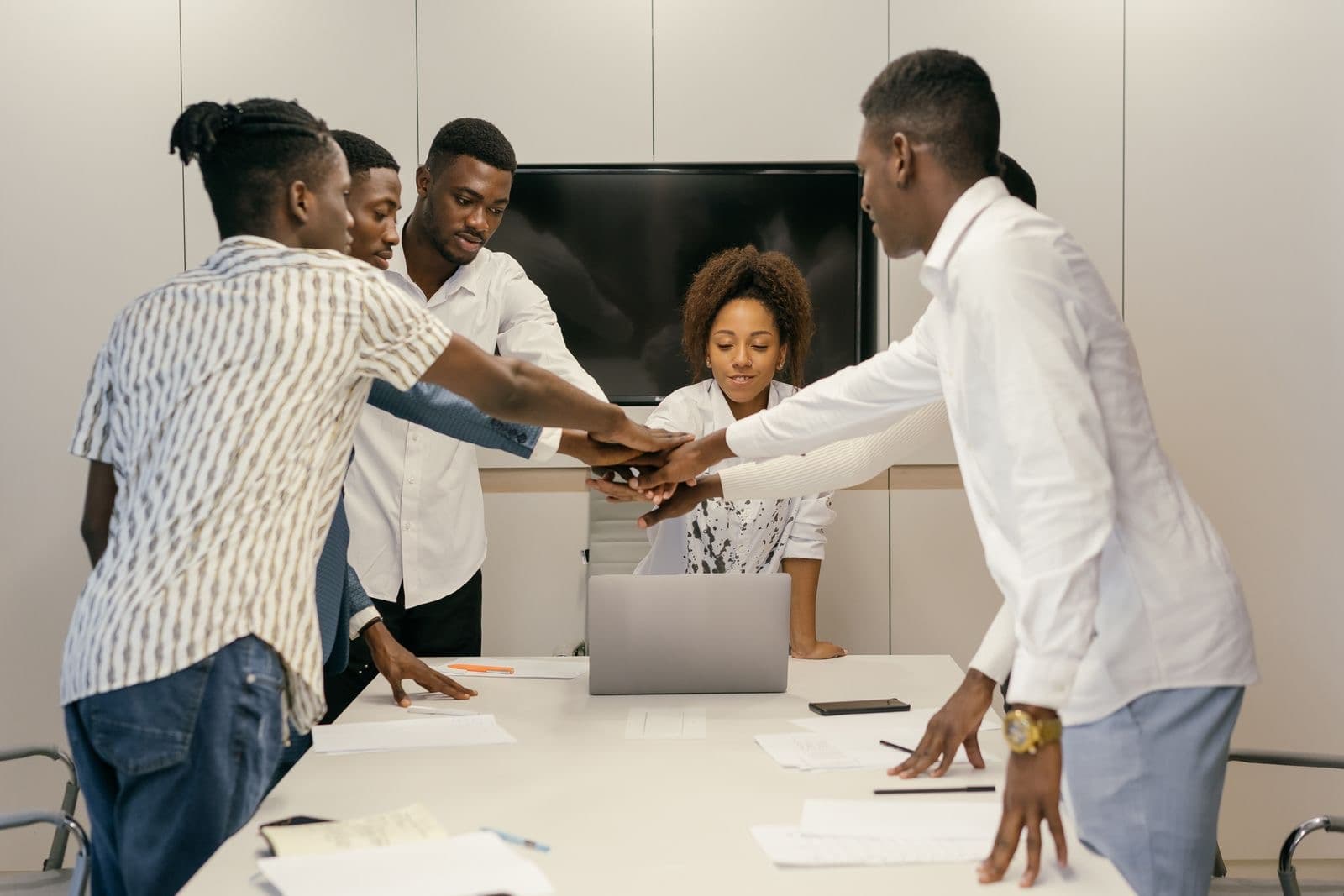 Colleagues joining hands over a table during a team meeting